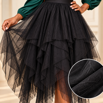 A black tiered tulle skirt worn by a model, shown from the waist down with one hand lifting the skirt to show its layered sheer texture. A circular inset in the bottom right corner provides a close-up of the black tulle fabric texture.